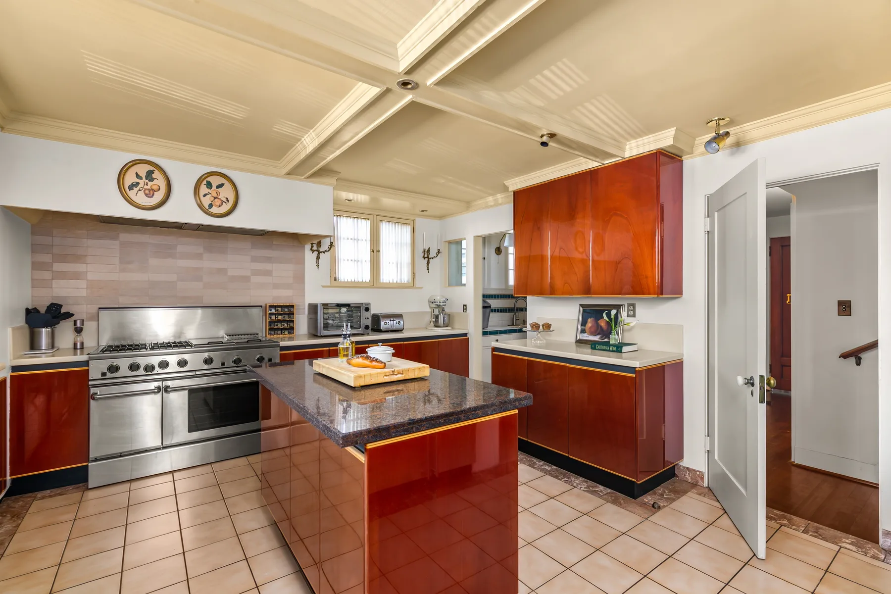 A bright kitchen with red cabinetry, stainless steel appliances, and a central island.
