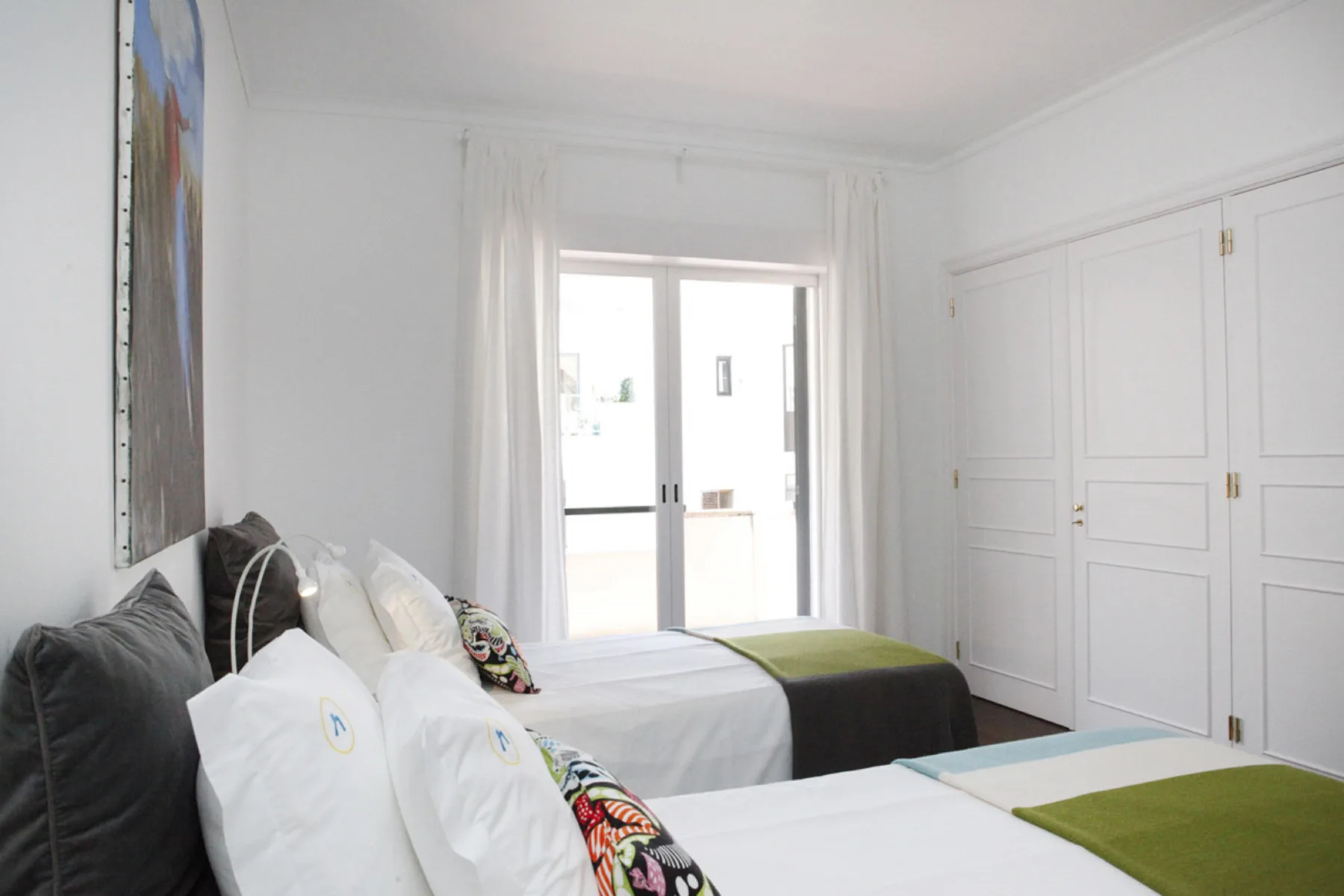 A bright bedroom with twin beds and white built-in wardrobes.