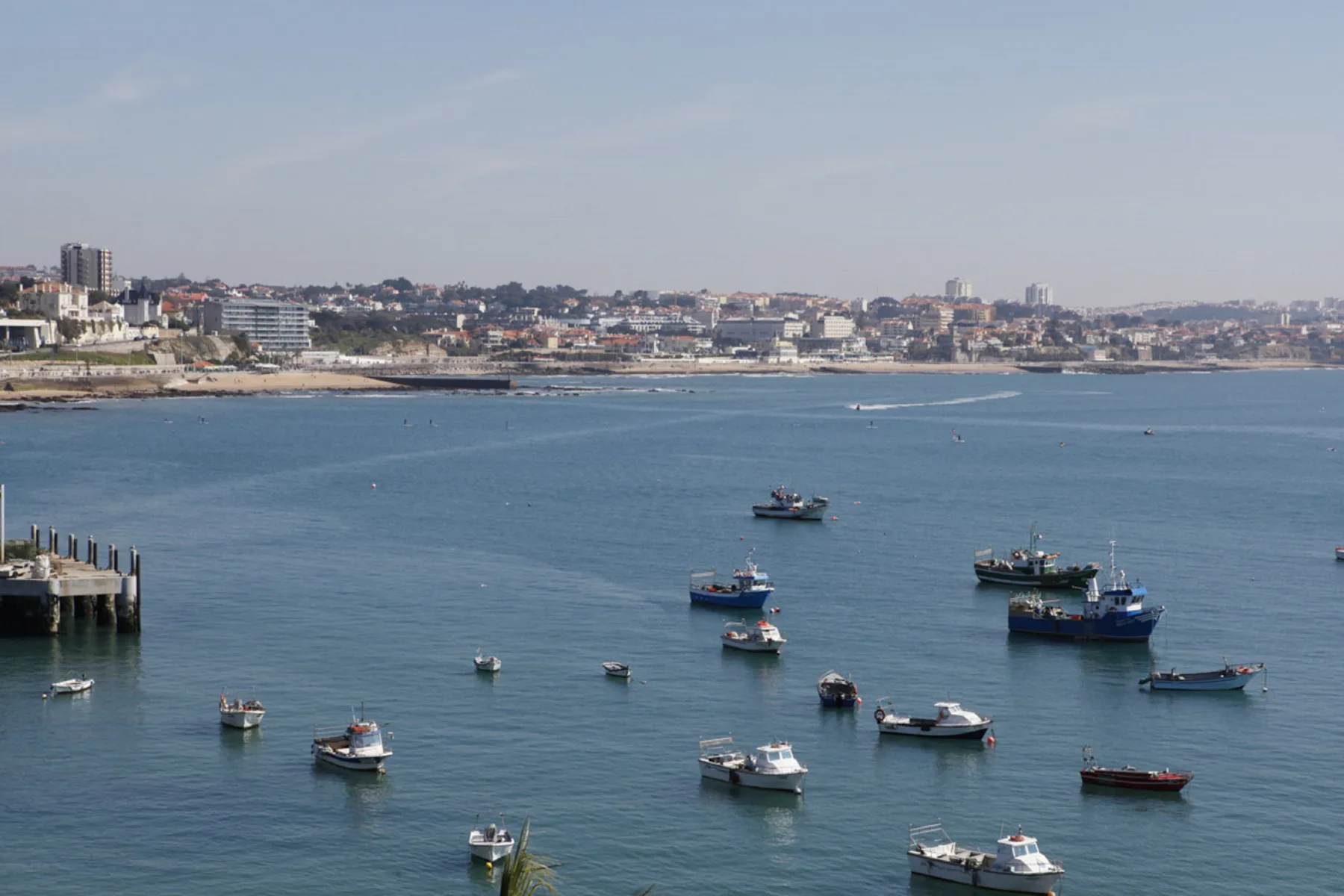 Una bahía costera con barcos en el agua y una ciudad junto a la orilla.