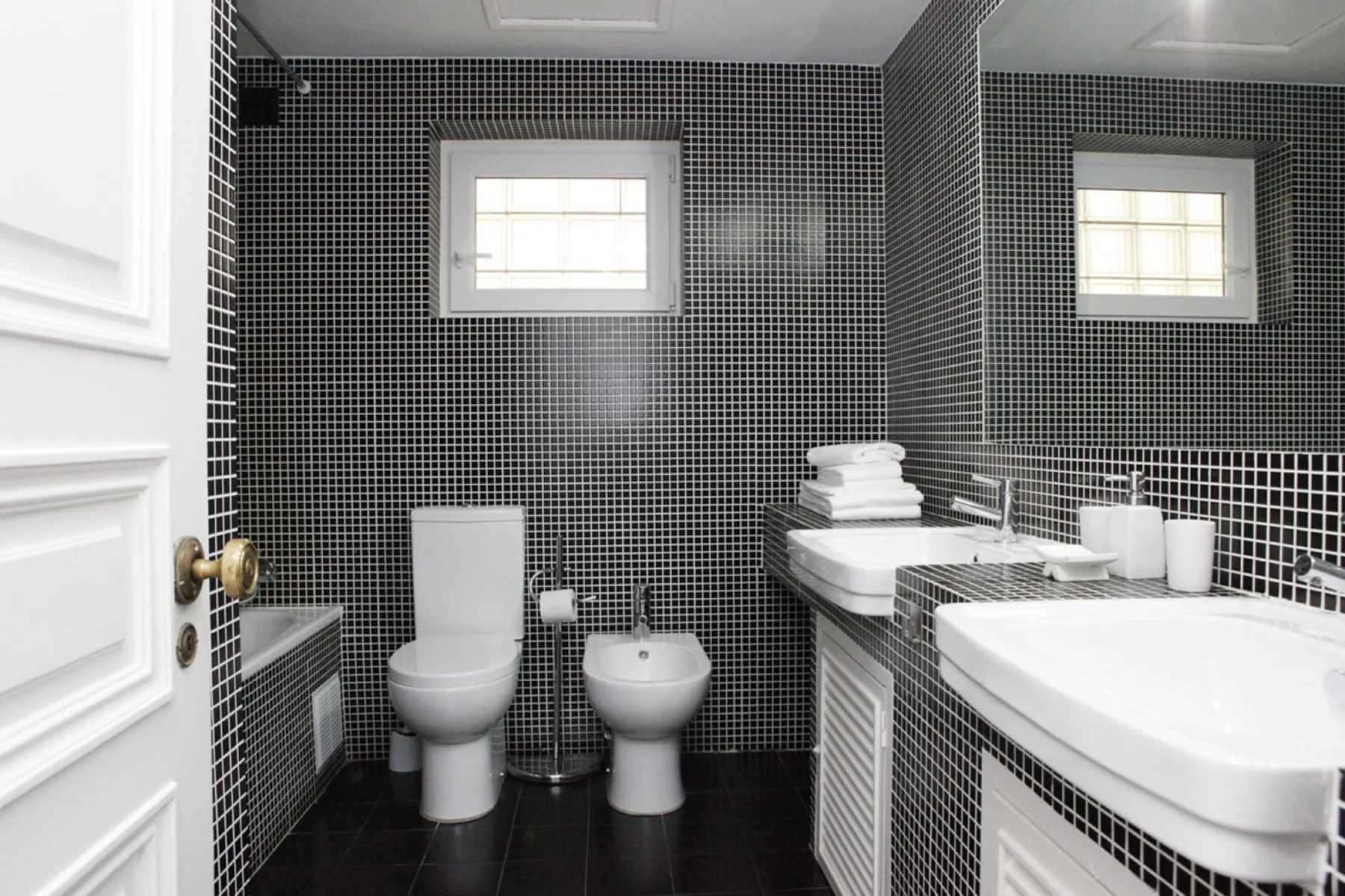 A tiled bathroom with a toilet, bidet, and sink.