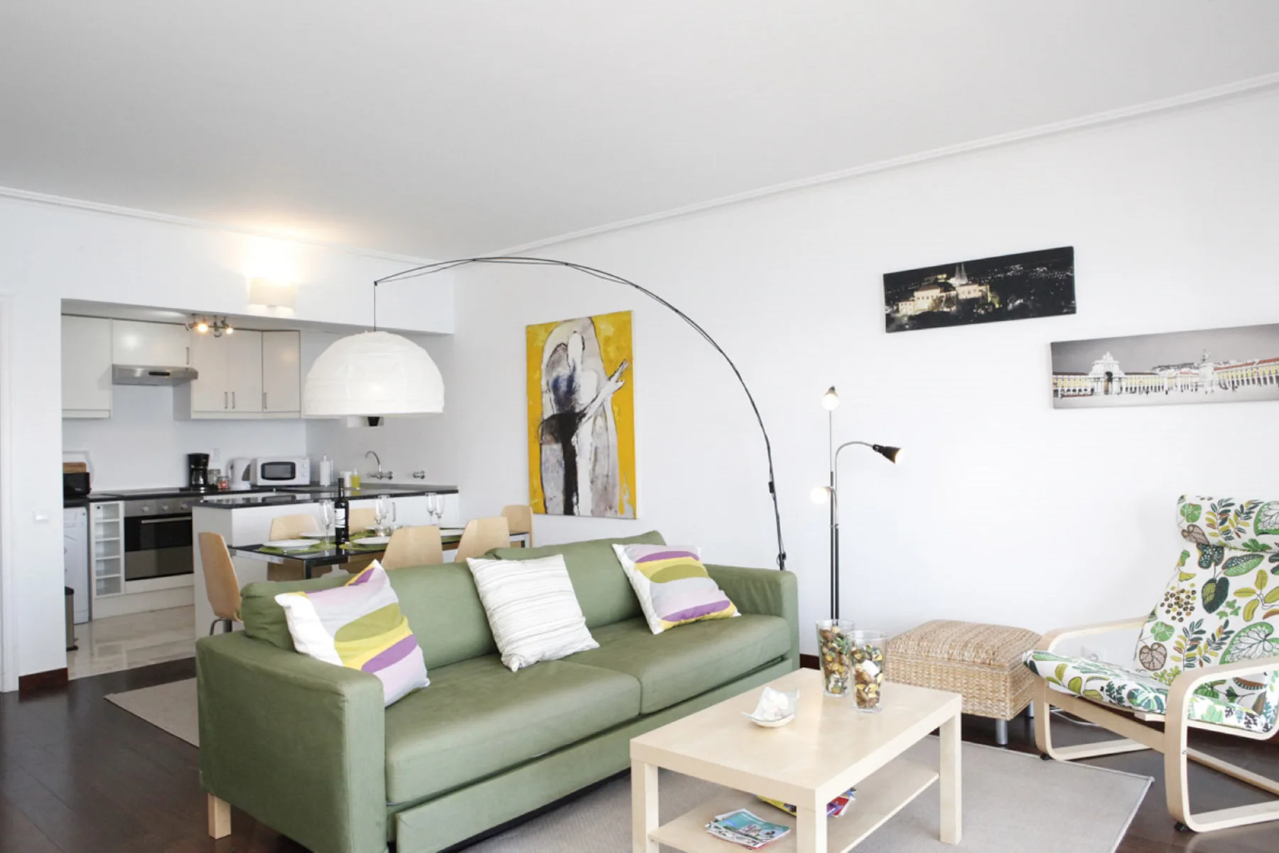 A bright living room with green seating and an open kitchen.