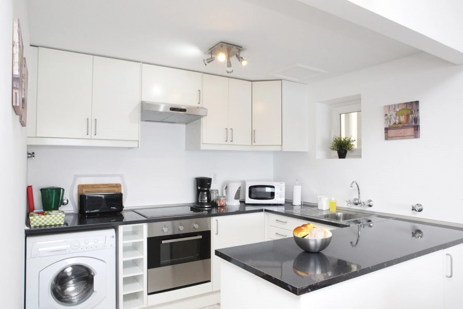 A bright kitchen with white cabinets, dark countertops, and built-in appliances.