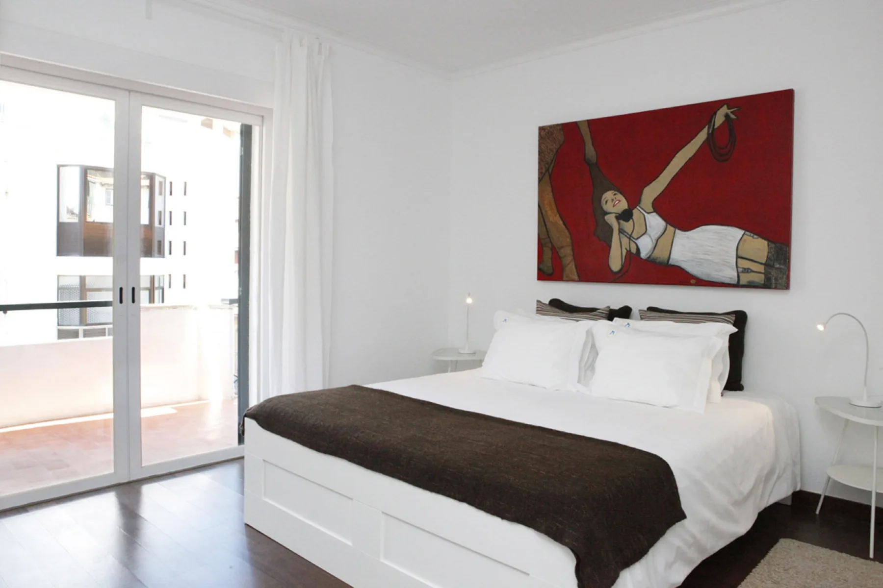 A bedroom with a white bed beneath a large red artwork.