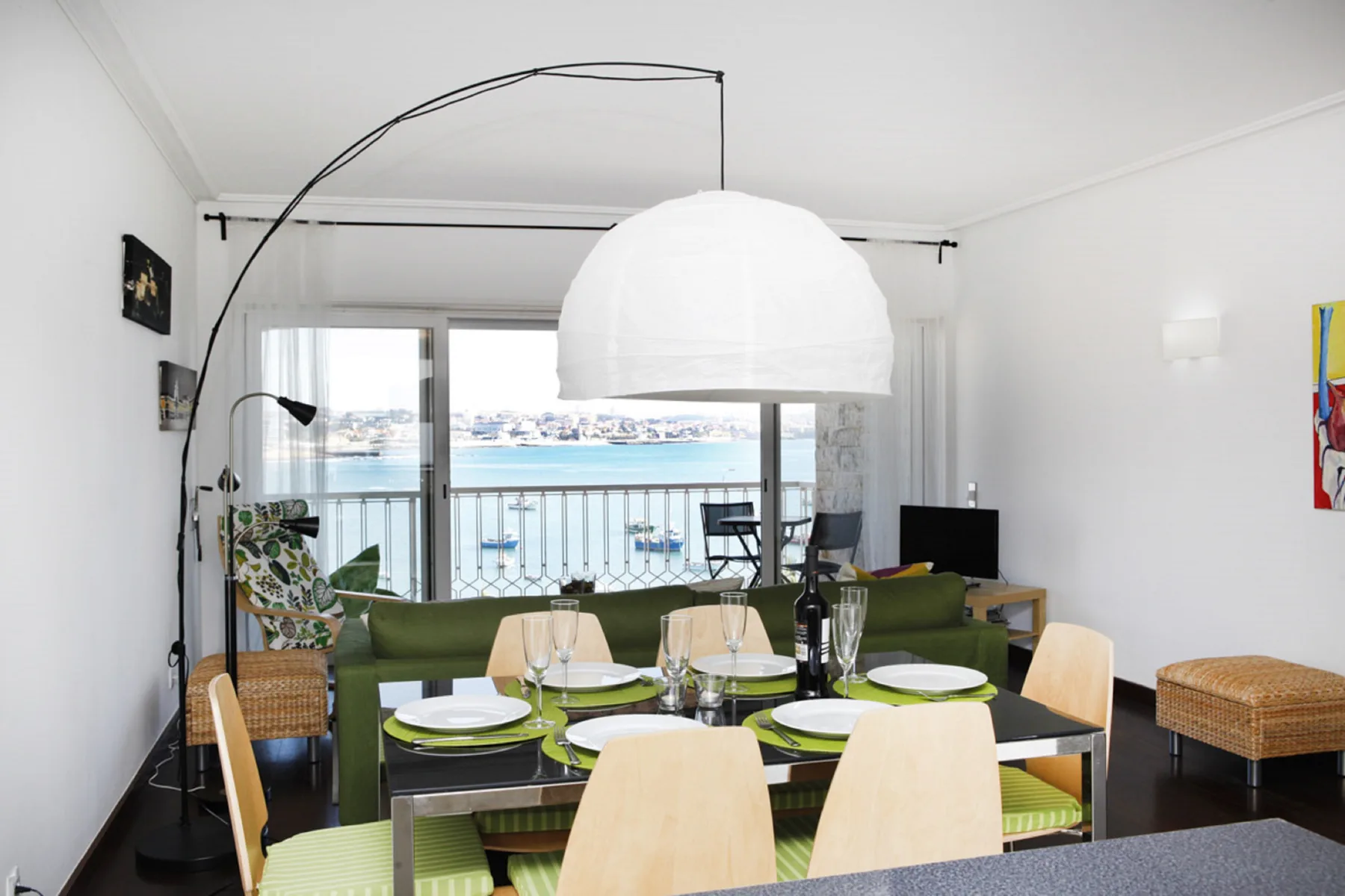 A bright living and dining area opens onto a balcony overlooking the water.