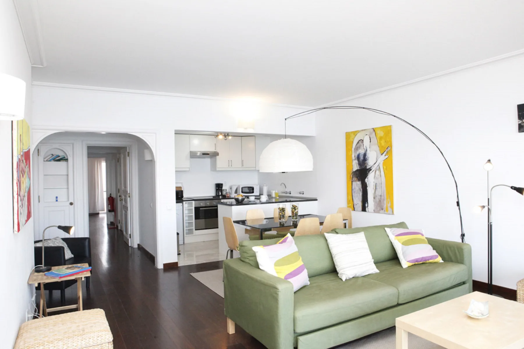 Living room with green seating and an open kitchen in the background.