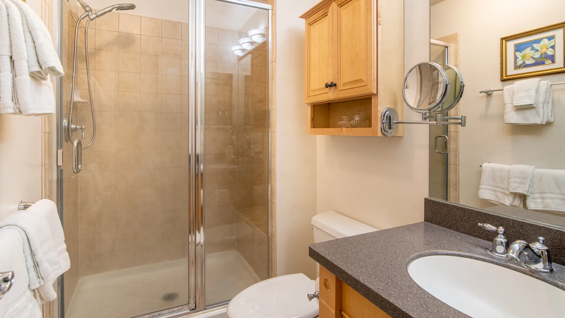 Un baño con ducha de vidrio, lavabo y gabinete de madera.
