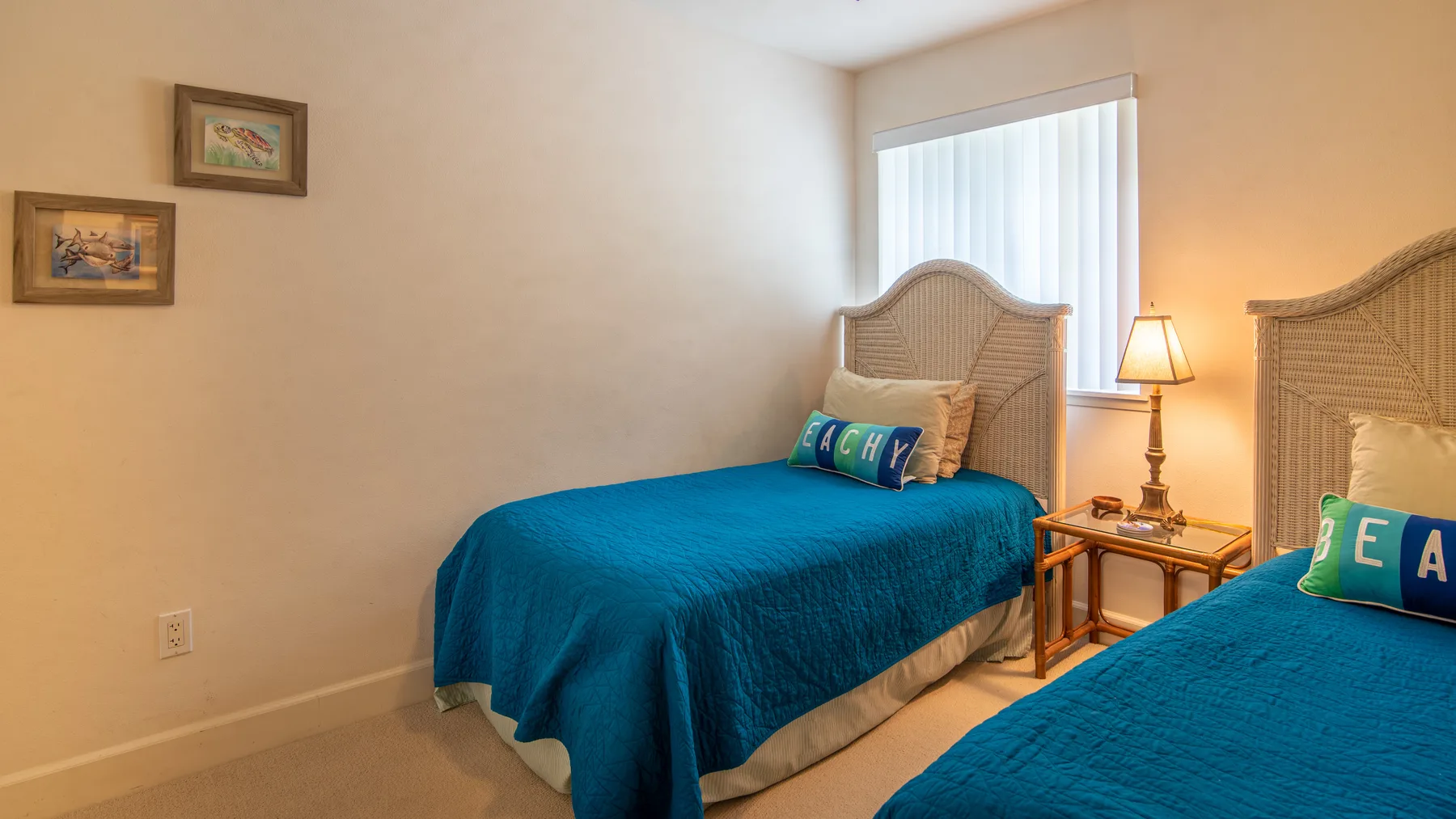 Un dormitorio con dos camas cubiertas con ropa de cama azul y una mesa de noche.