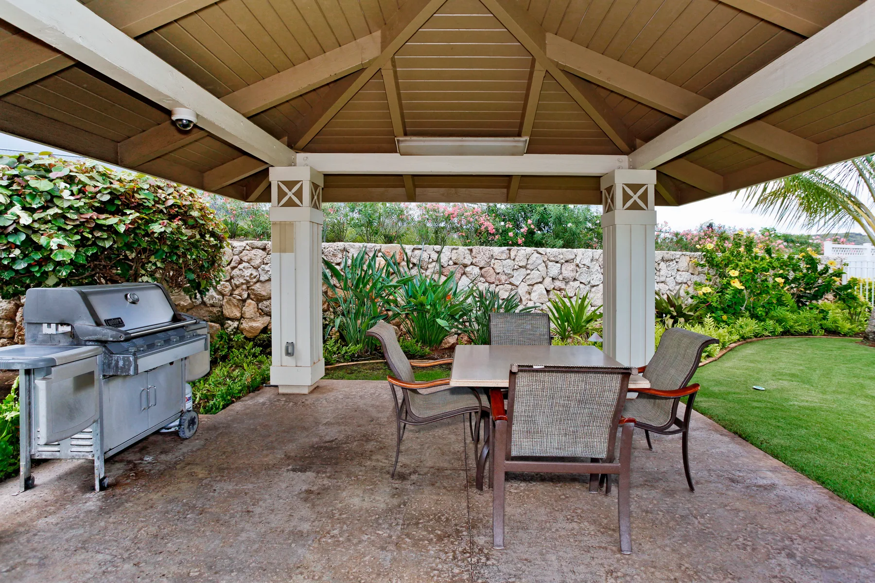 Un patio exterior cubierto con una mesa de comedor y una parrilla junto al césped.
