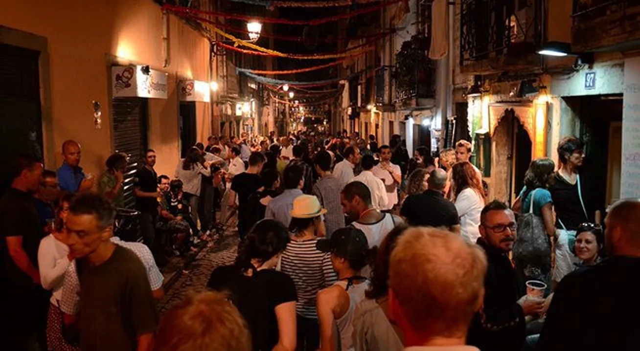 A crowded, brightly lit pedestrian street lined with storefronts at night.
