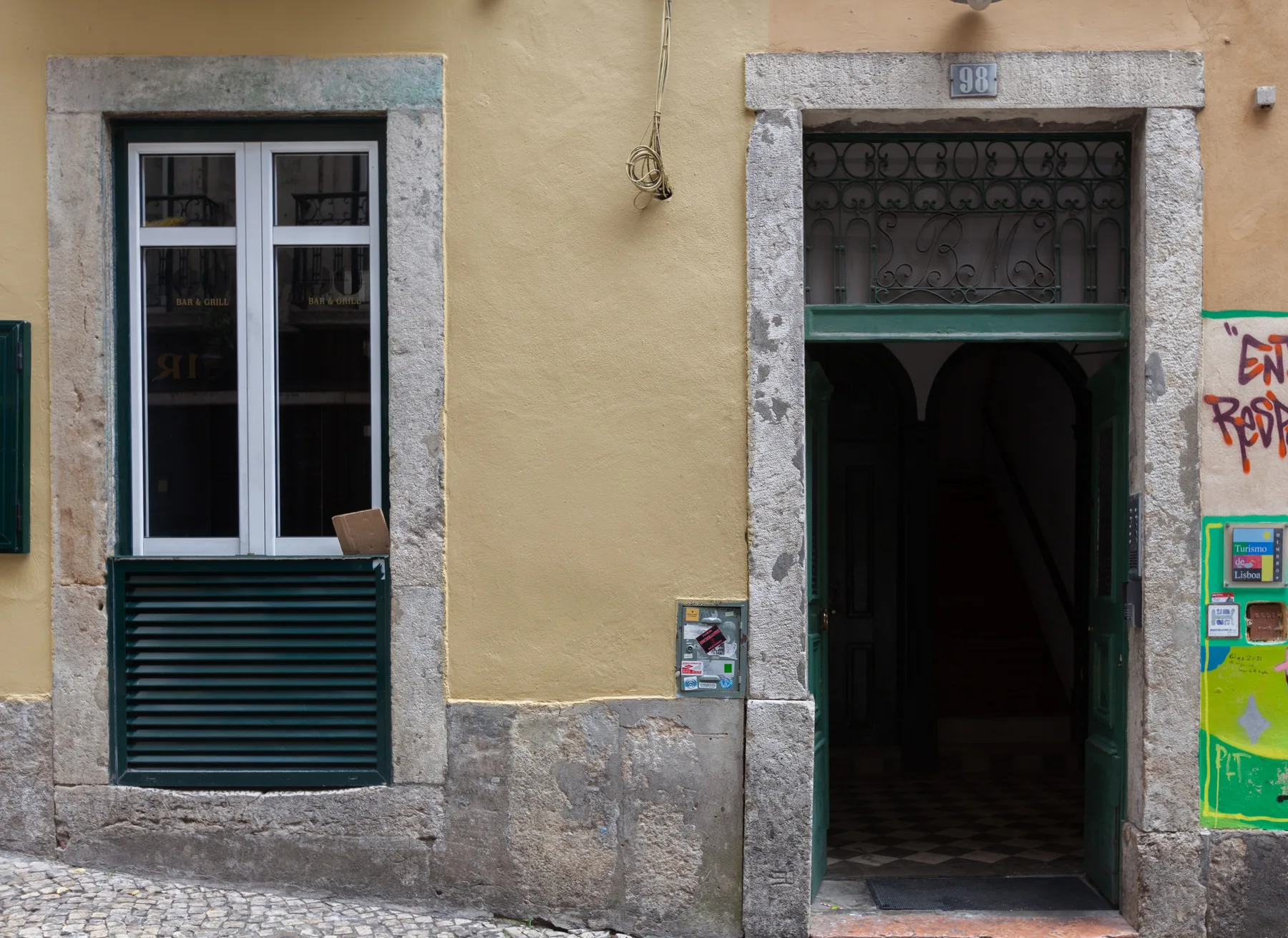A yellow building facade with a window and an open doorway.