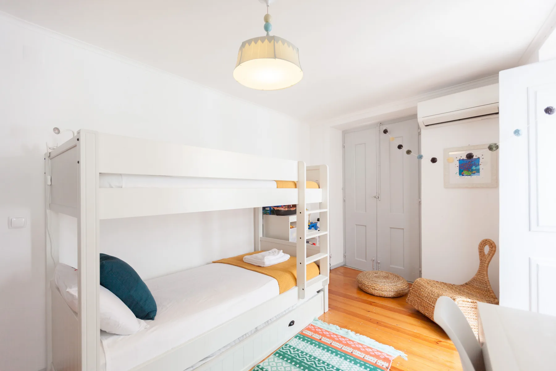A bright bedroom with bunk beds and colorful bedding.