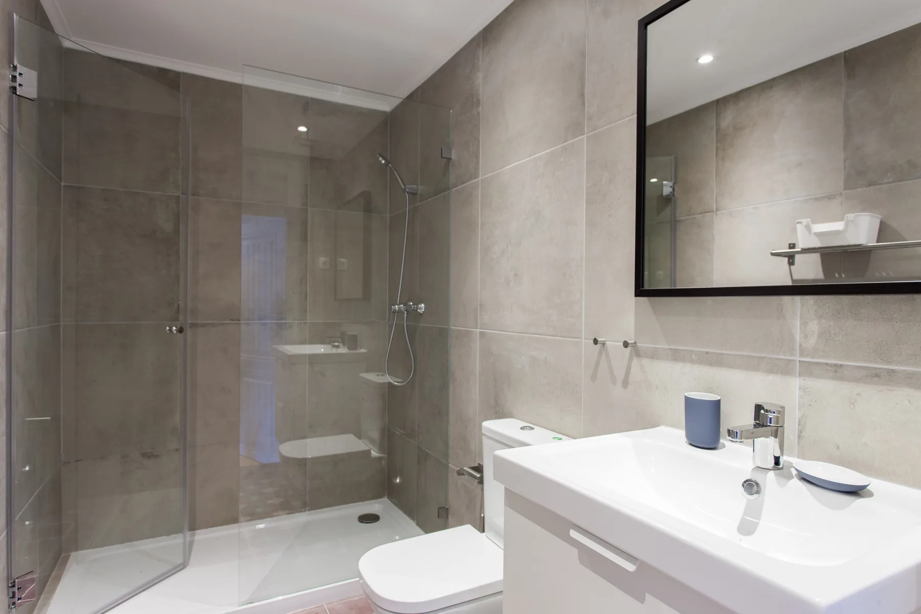 A modern bathroom with a glass shower and a white vanity.