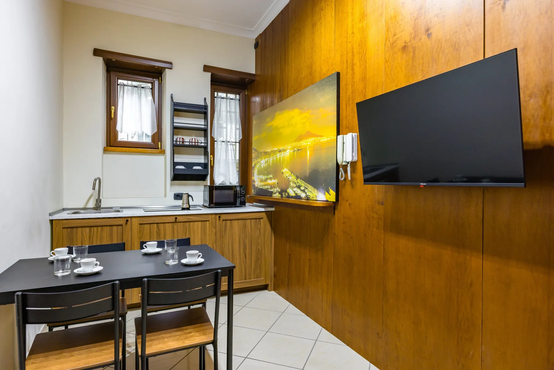 Un pequeño comedor con mesa, encimera y pantallas montadas en la pared.
