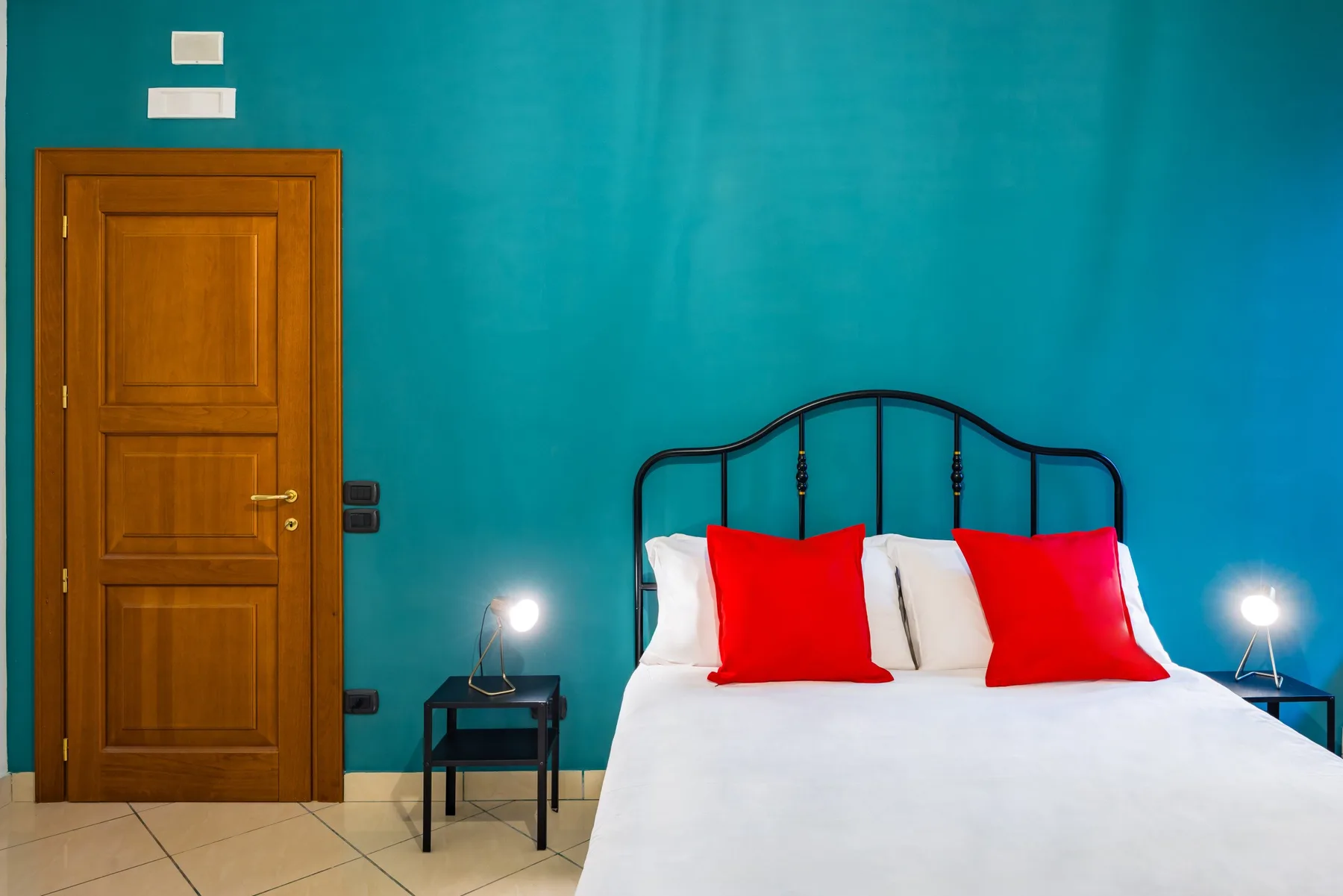 Un dormitorio con una cama junto a una pared turquesa y una puerta de madera.