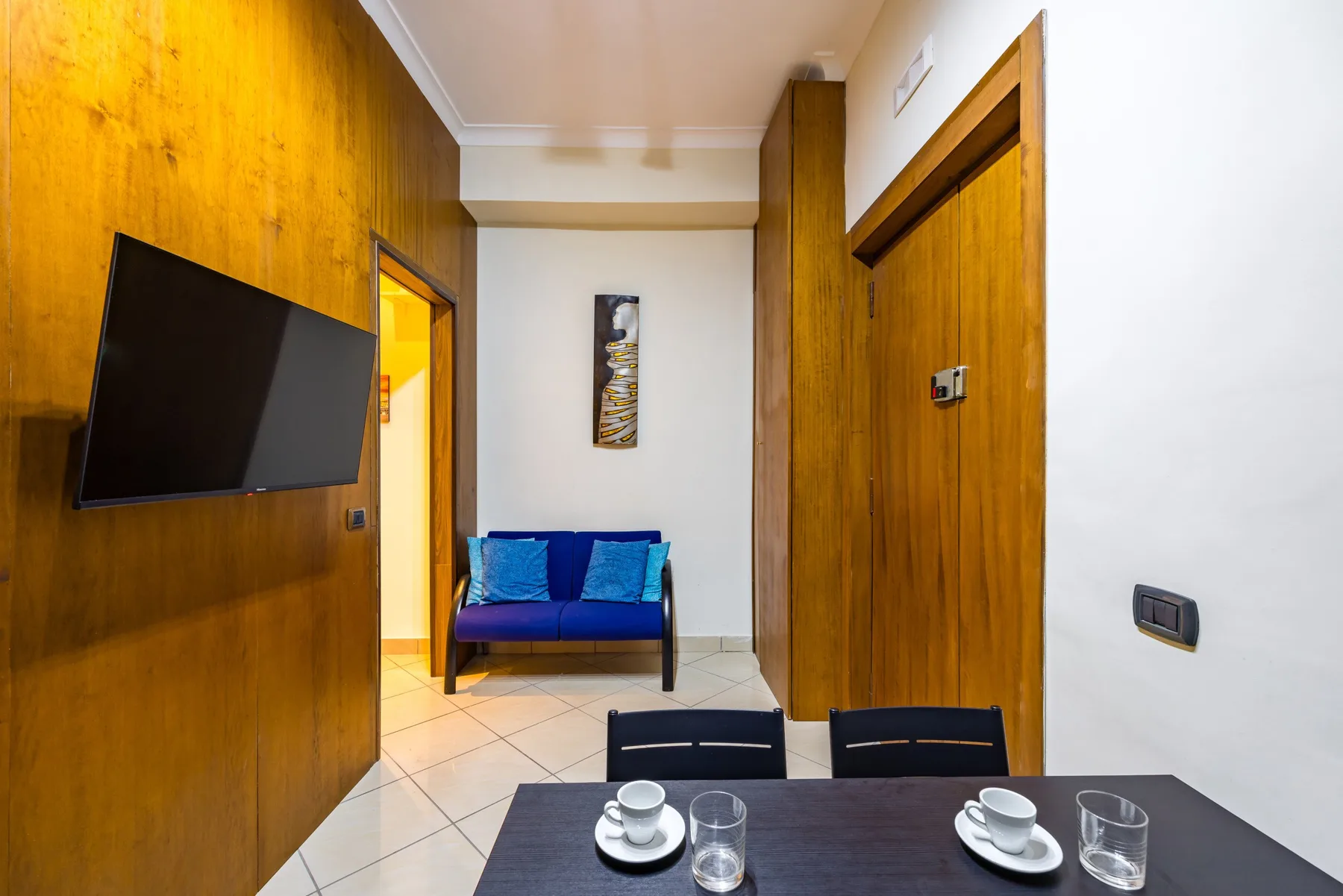 Un pasillo con una pequeña zona de estar y una mesa preparada con tazas y vasos.