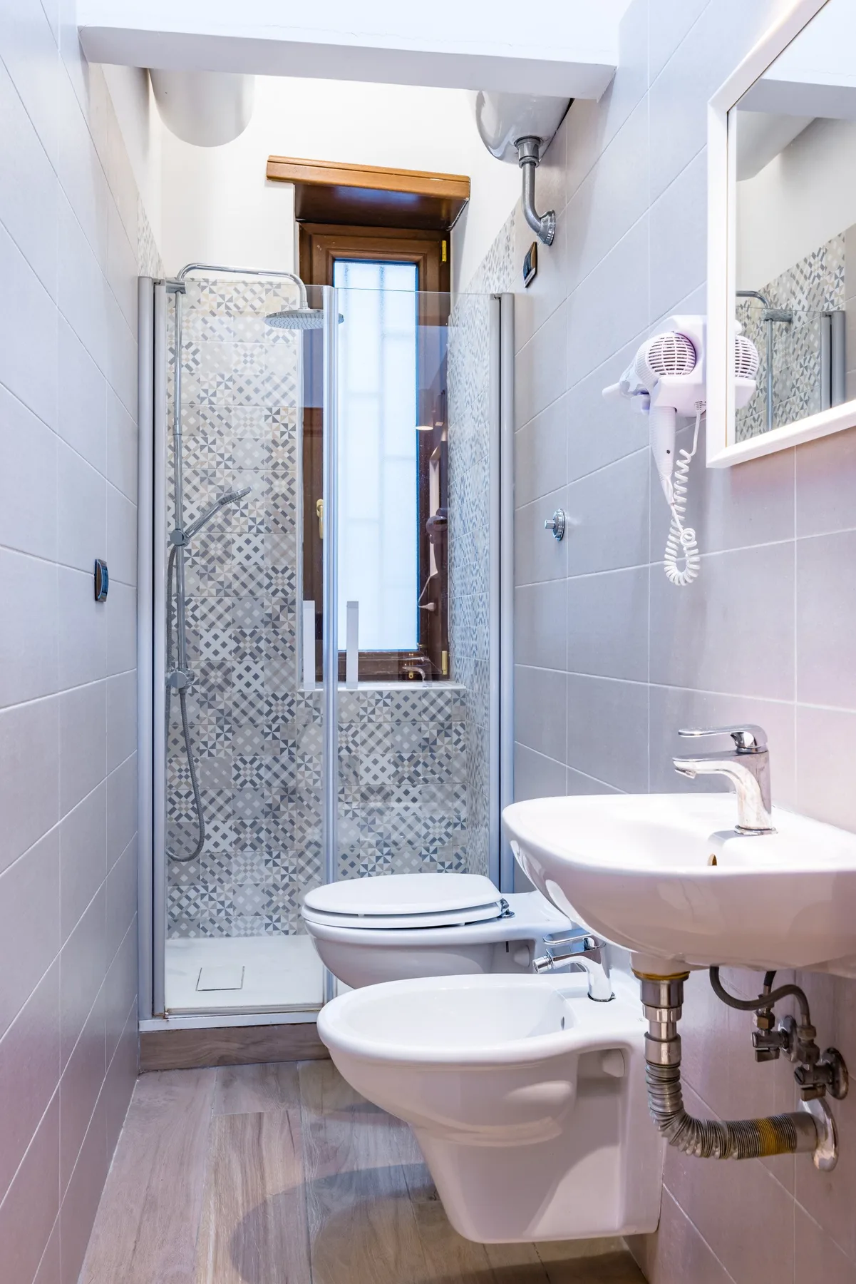 Un baño estrecho con ducha de vidrio, inodoro y bidé.