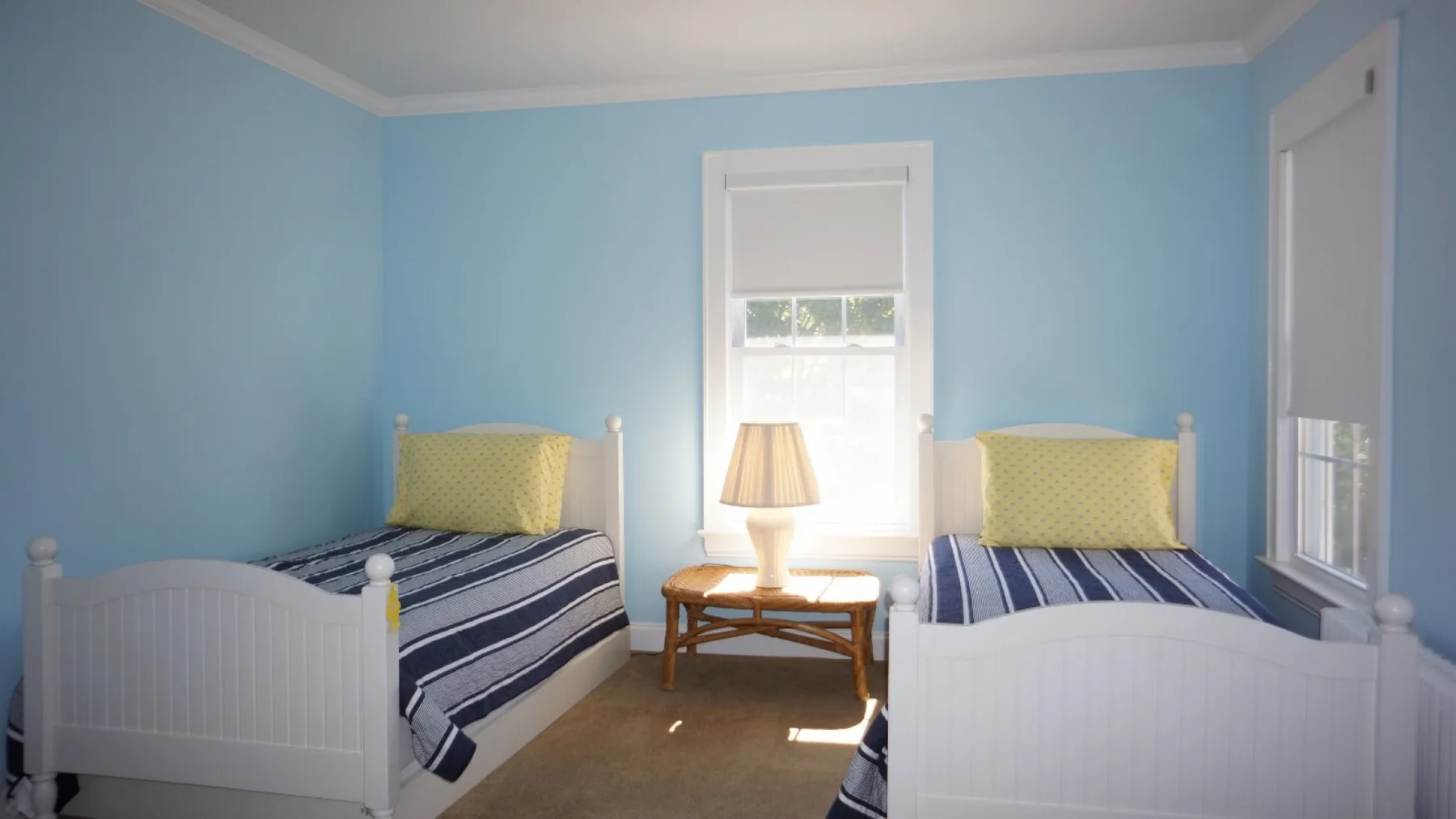 Un dormitorio azul con dos camas individuales y una mesa pequeña entre ellas.