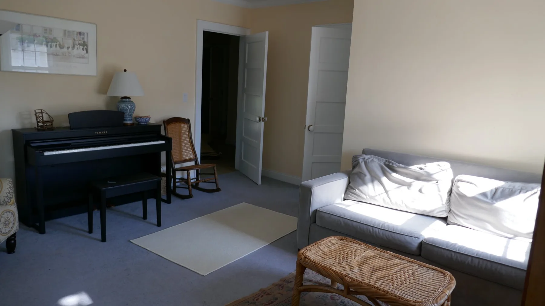 Una sala de estar con un piano, asientos y una mesa de centro tejida.