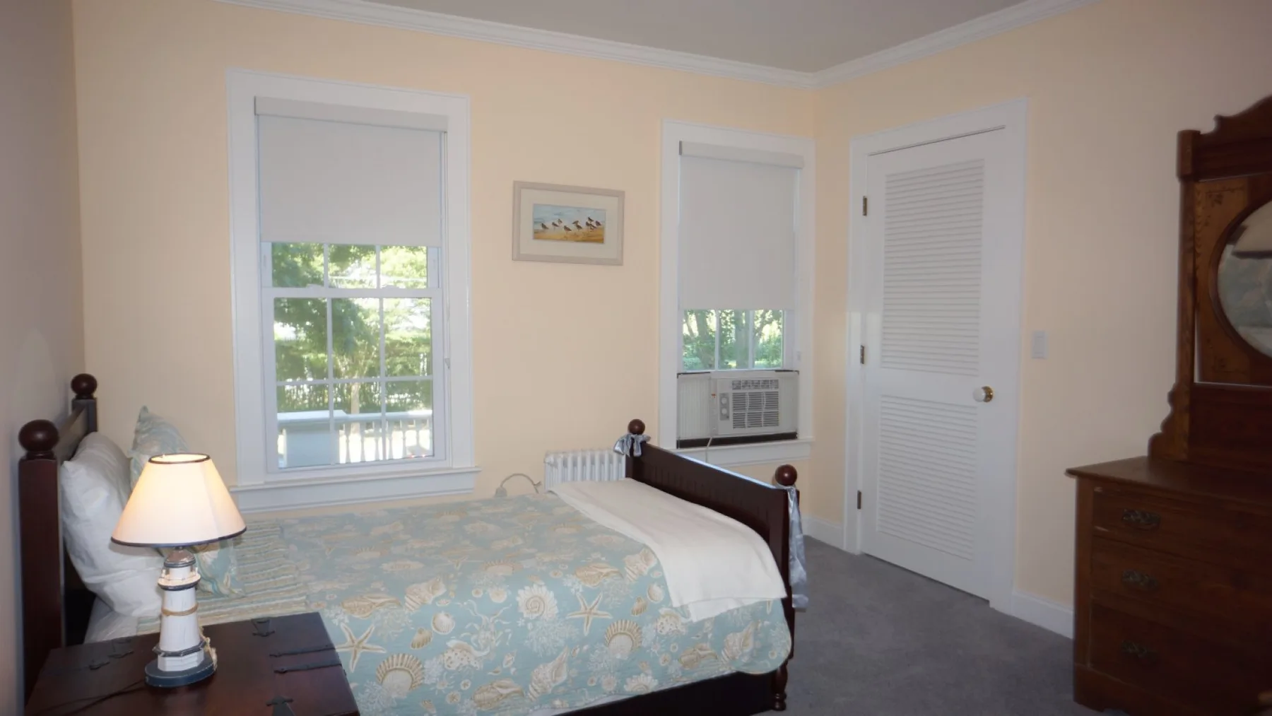 Un dormitorio con una cama, una lámpara de noche y dos ventanas.