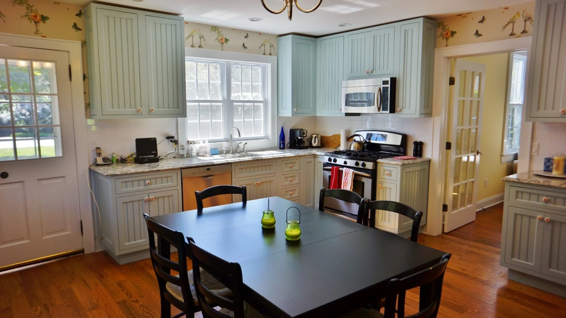 Una cocina con gabinetes azul claro, una isla central y una mesa de comedor.
