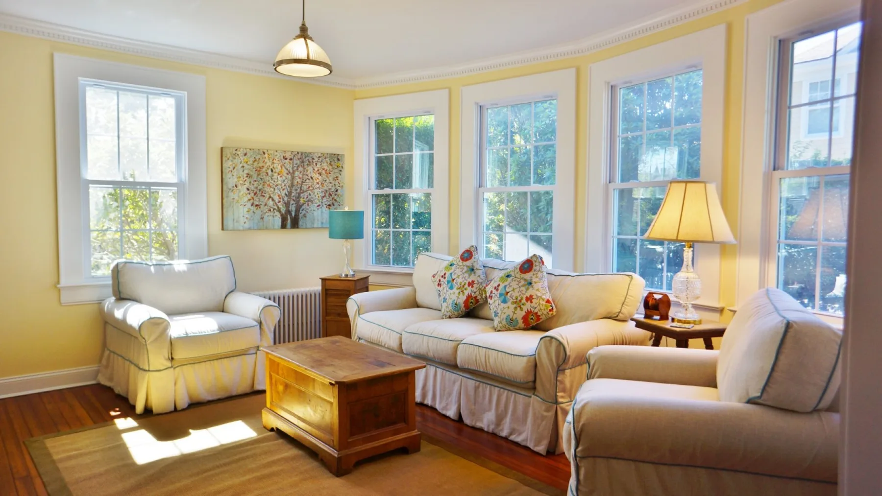 Una sala luminosa con asientos acolchados, ventanas altas y una mesa de centro de madera.