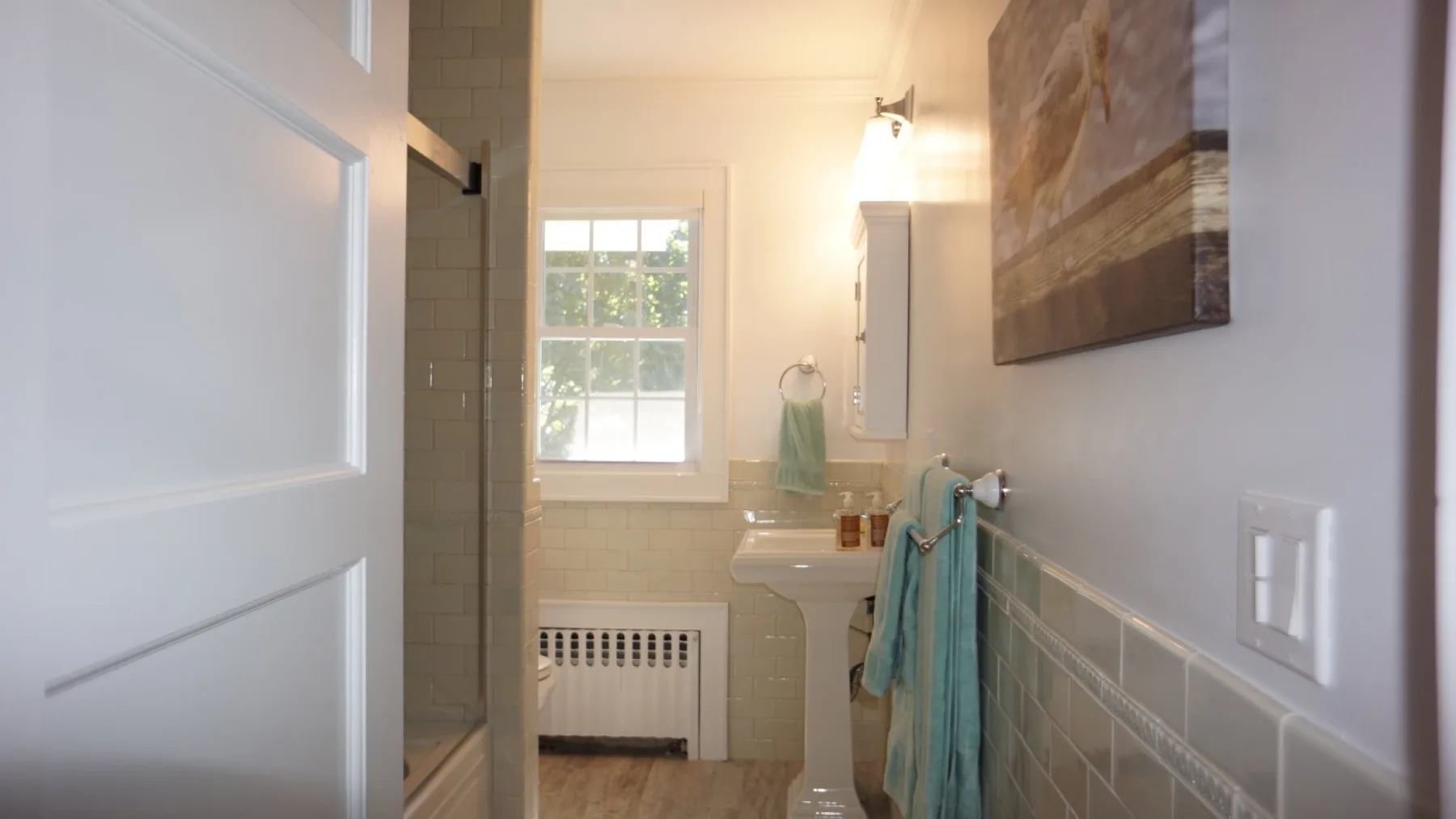 Un baño con lavabo, paredes de azulejos y una ventana.