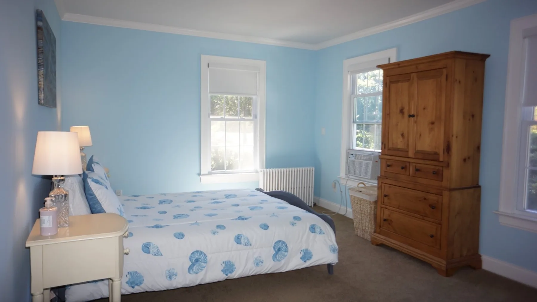Un dormitorio con una cama, una mesita de noche y un armario de madera.