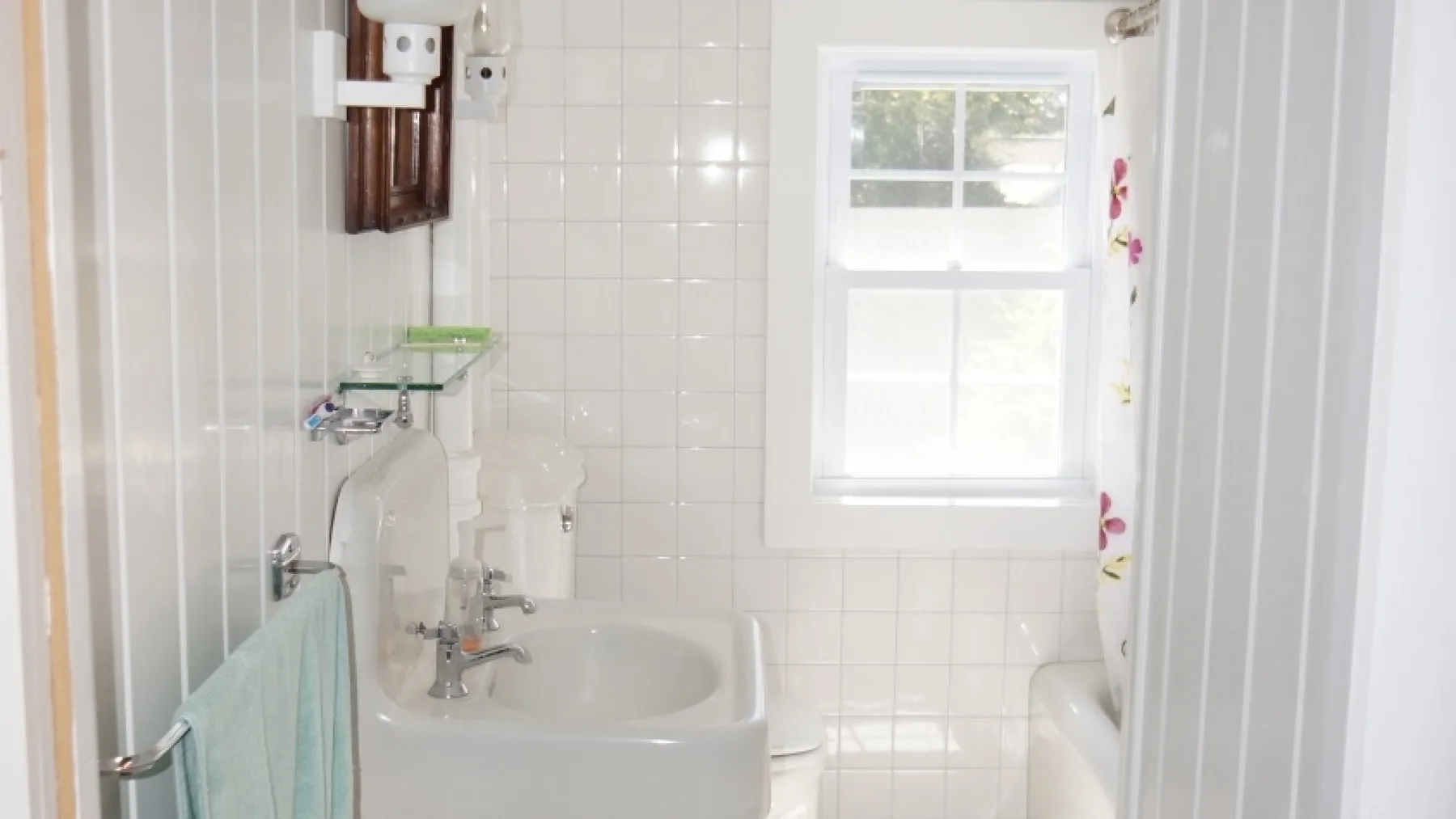 Un baño alicatado con bañera, lavabo y ventana.