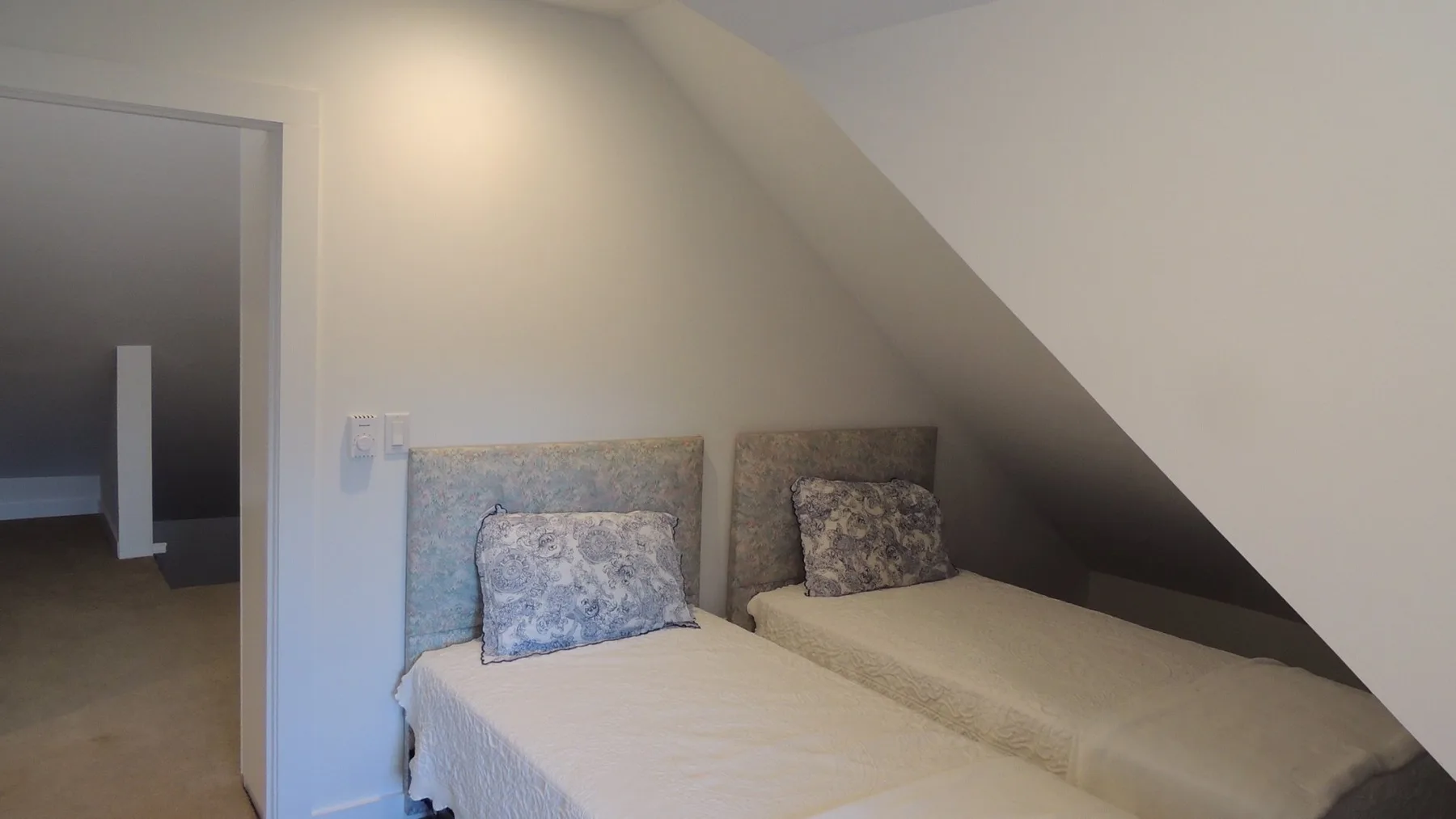 Un dormitorio con dos camas individuales bajo un techo inclinado.