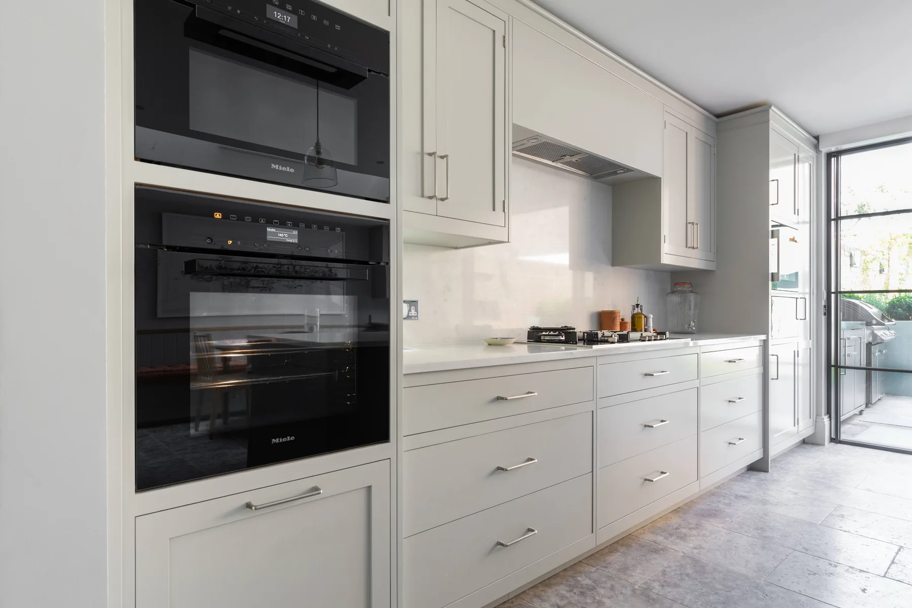 Una cocina moderna y luminosa con gabinetes blancos y electrodomésticos integrados.