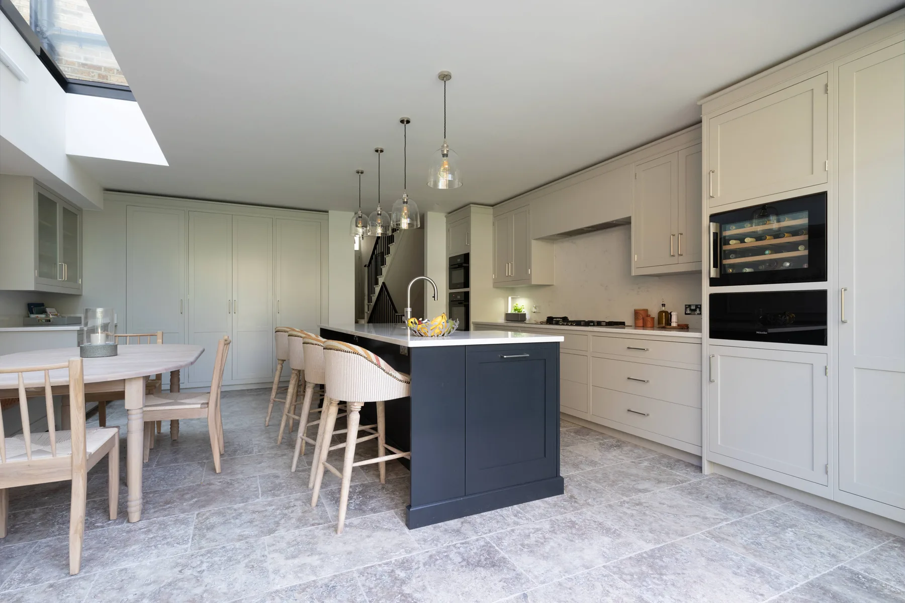 Una cocina luminosa con zona de comedor, isla central y mesa.