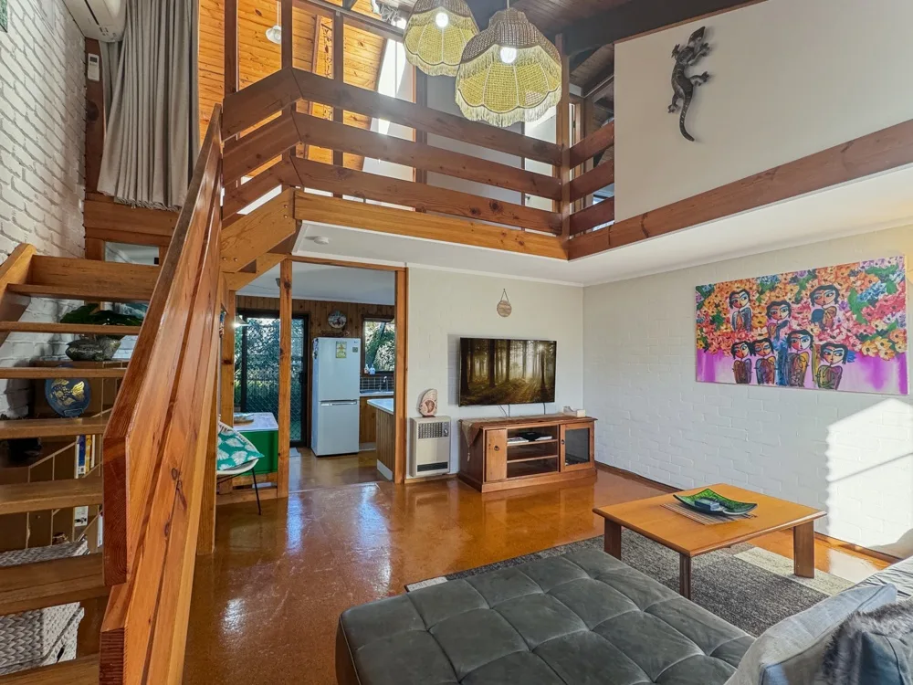 Sala de estar de doble altura con una escalera de madera.