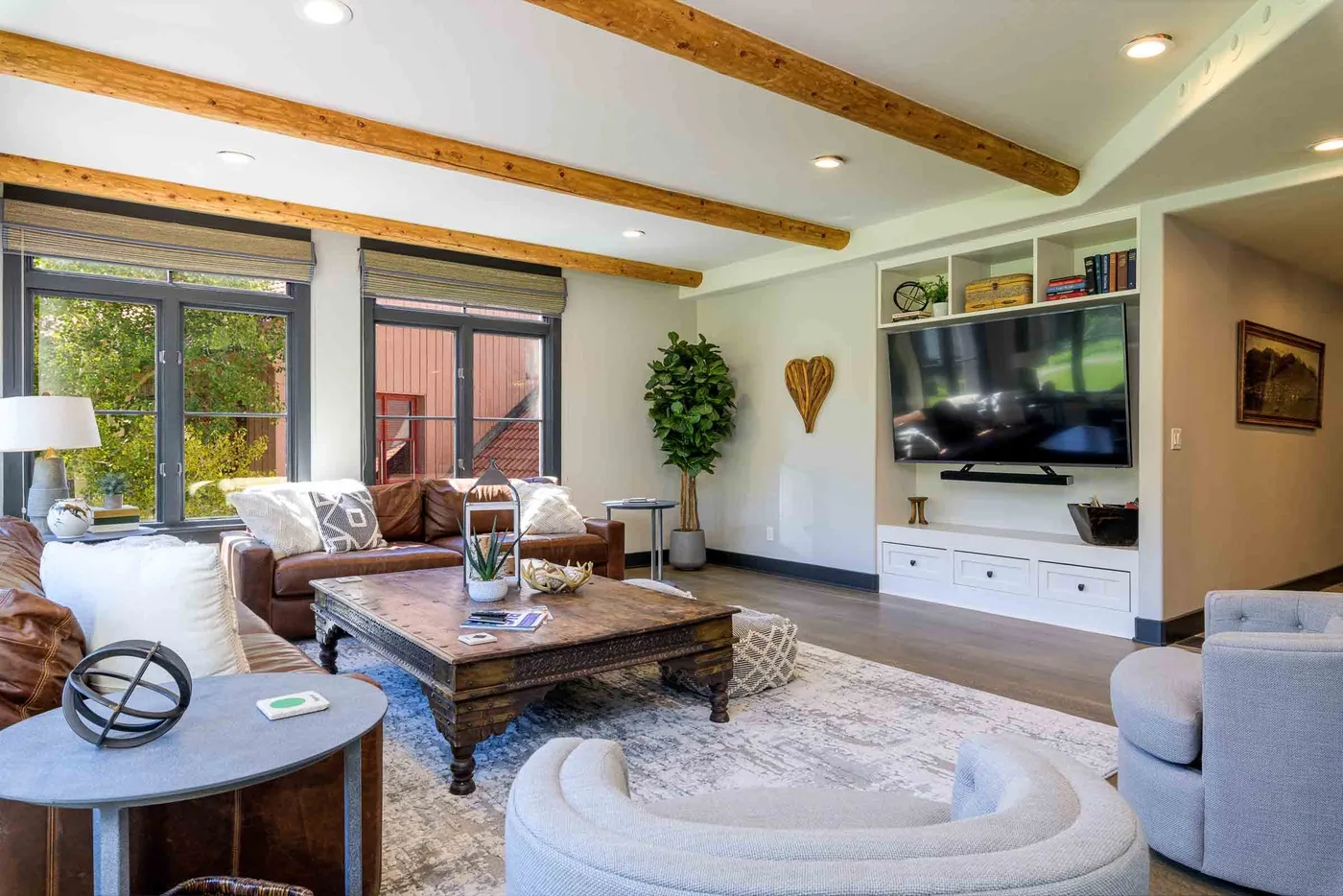 A bright living room with seating, a coffee table, and a television.