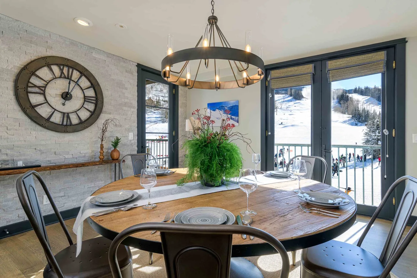 A dining area with a set table, large windows, and a snowy view outside.