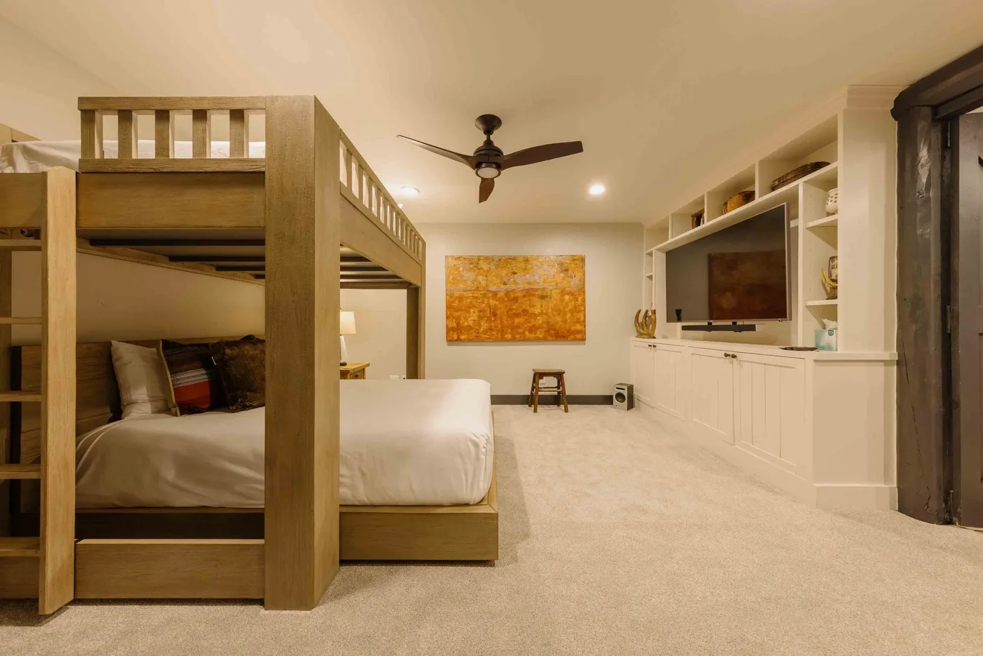 A bedroom with a wooden bunk bed and built-in shelving along the wall.