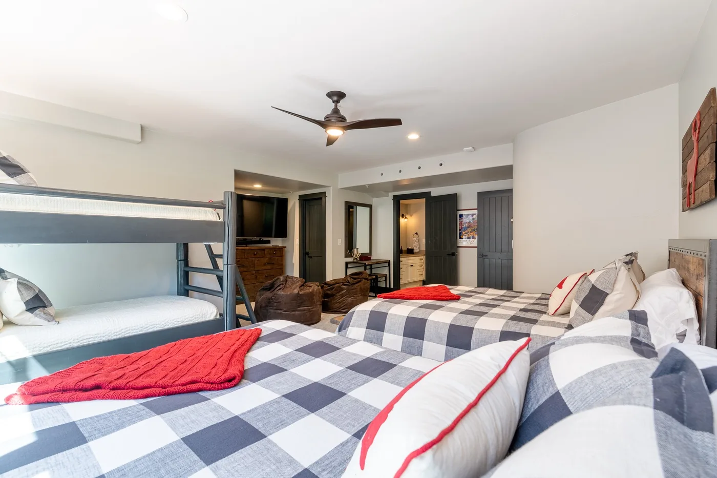 A bedroom with patterned bedding, a bunk bed, and a ceiling fan.