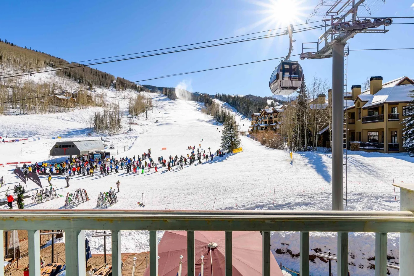 A snowy ski slope with skiers gathered below a chairlift.