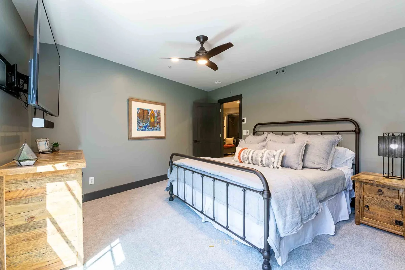 A bedroom with a metal bed, bedside table, and ceiling fan.