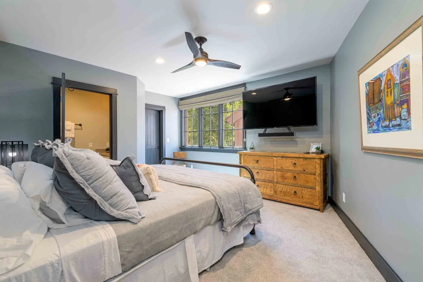 A bedroom with a bed, a dresser, and a wall-mounted television.