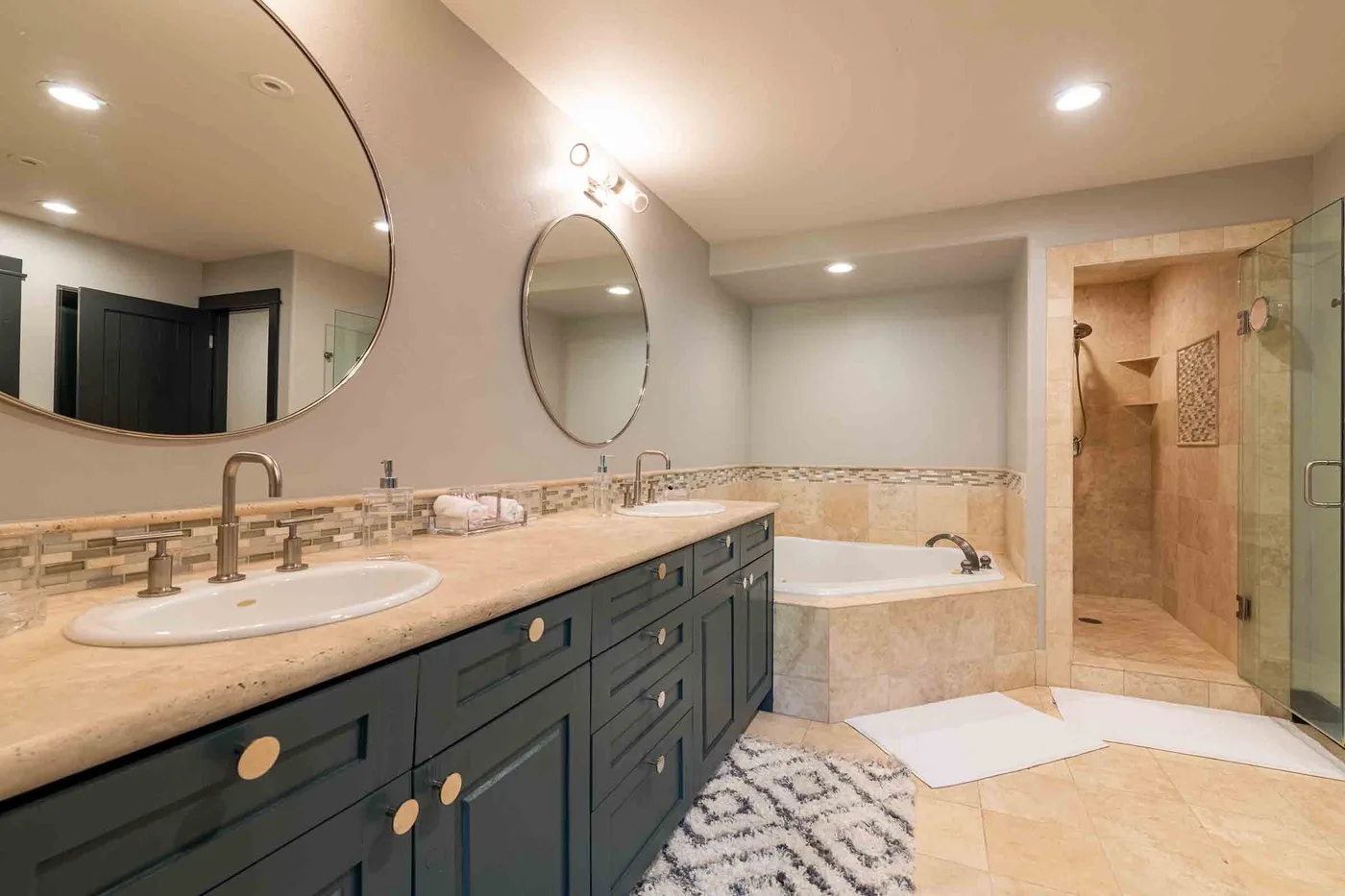A spacious bathroom with a long vanity, bathtub, and glass-enclosed shower.