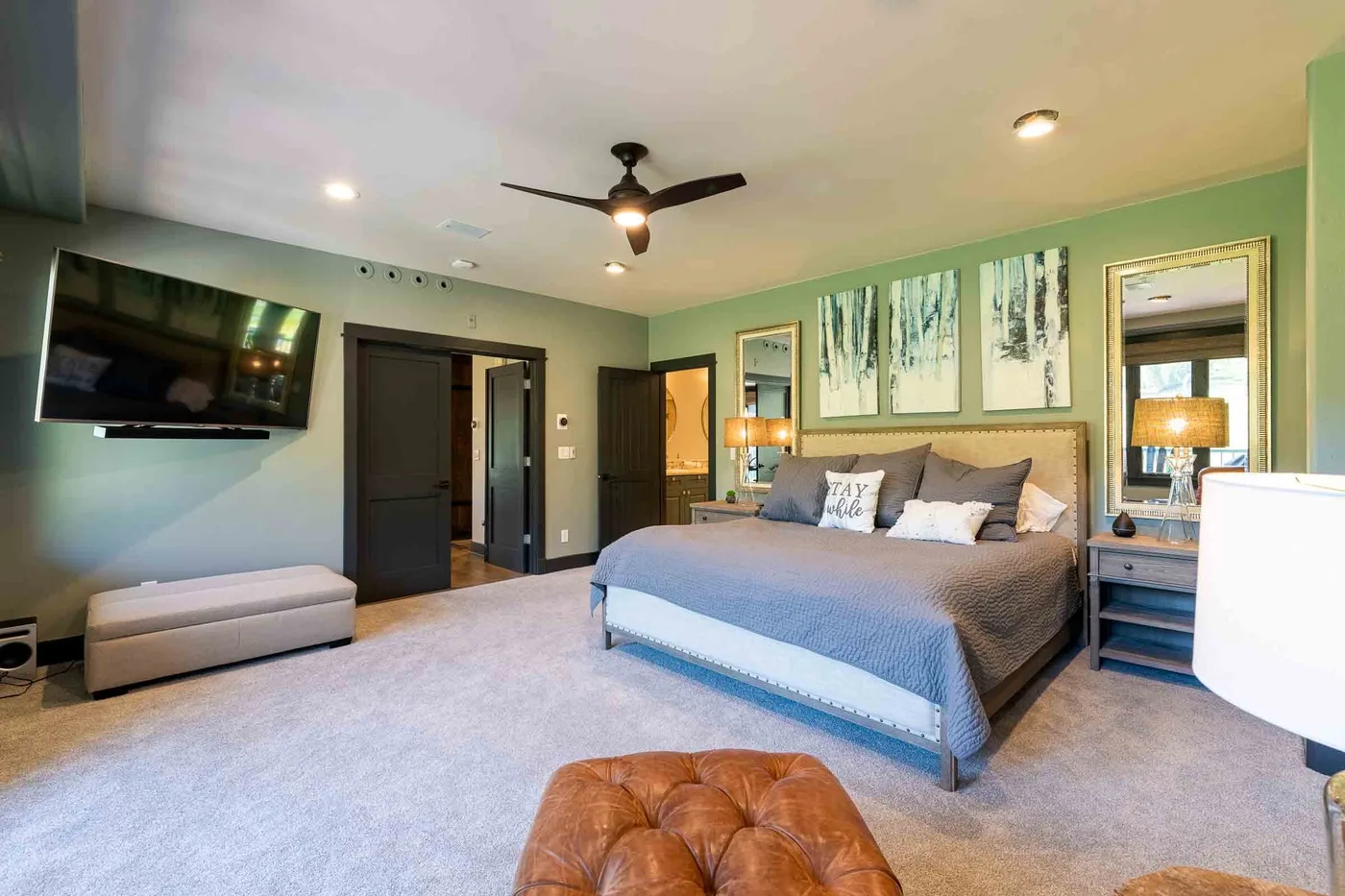 A bedroom with a large bed, wall-mounted television, and green walls.