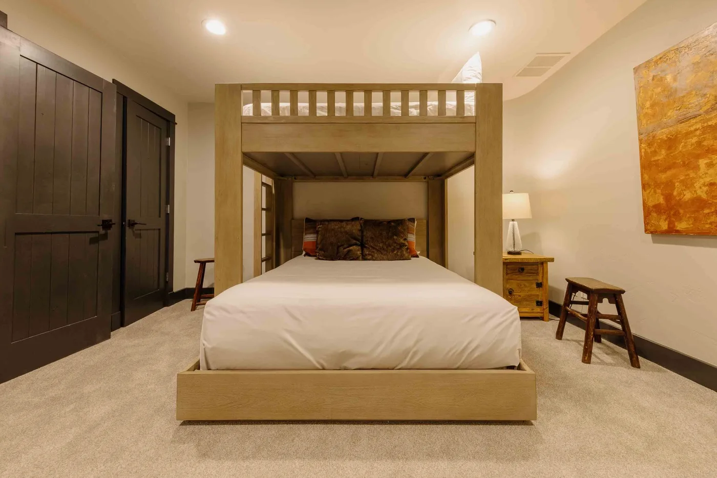 A bedroom with a raised wooden bed frame and white bedding.