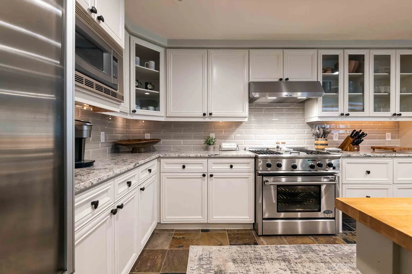 A bright kitchen with white cabinetry, stainless steel appliances, and a tiled backsplash.