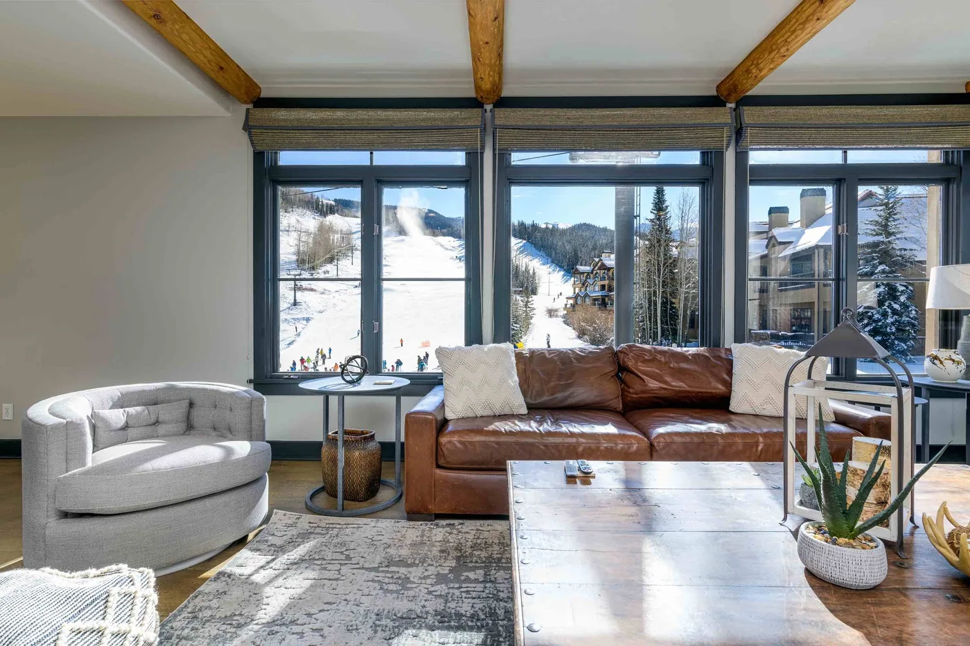 A living room with broad windows overlooking a snowy mountain slope.