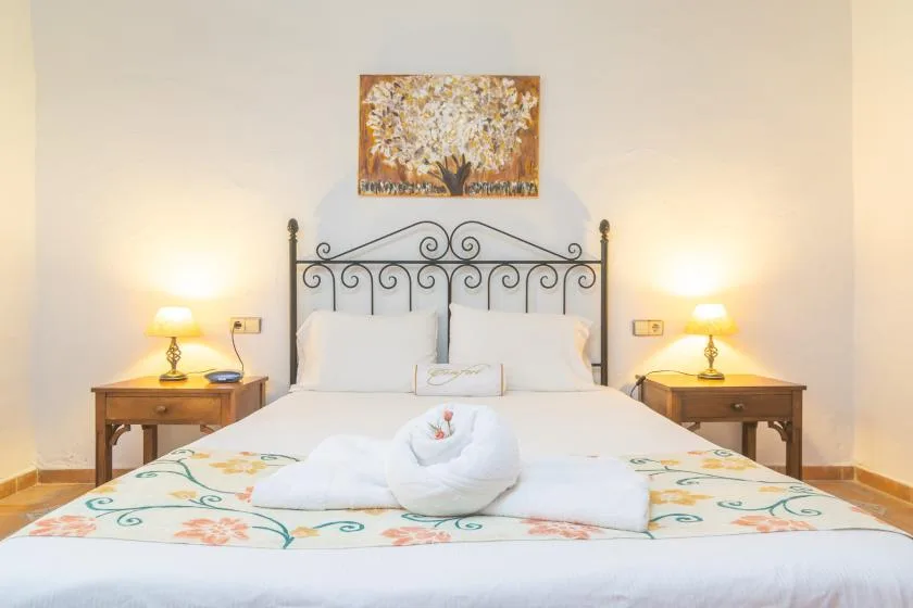 A bedroom with a white bed, decorative black headboard, and matching bedside tables.
