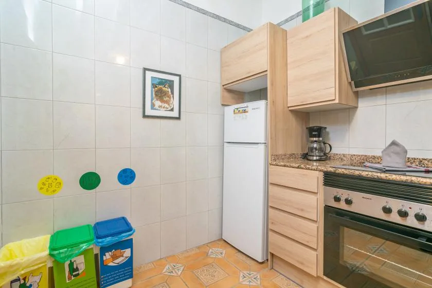 A tiled kitchen with wooden cabinets, a refrigerator, and a stove.