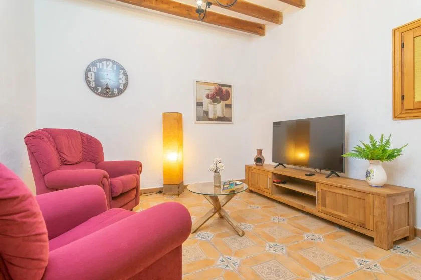 A living room with pink seating, a television, and a wooden media cabinet.