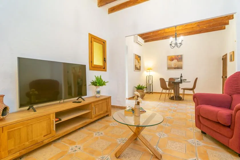 A living and dining area with seating, a television, and a glass coffee table.