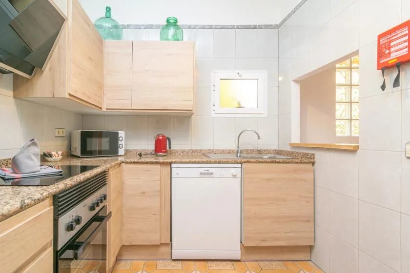 A compact kitchen with light wood cabinets, a countertop, and a dishwasher.