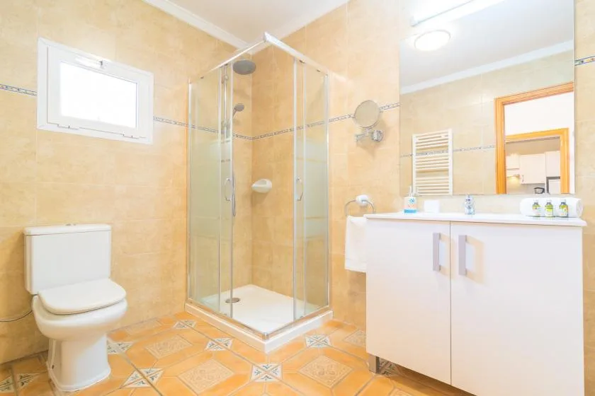A bright bathroom with a glass shower, toilet, and sink vanity.